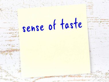 Tahta duvarda el yazısıyla yazılmış tat alma duyusu olan sarı yapışkan bir not.