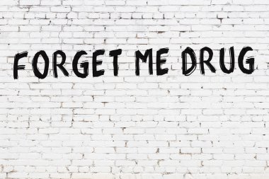 Üzerinde yazı olan beyaz tuğla duvar. Unutun beni. Siyah boyayla yazılmış uyuşturucu.