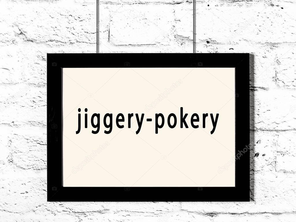 Black wooden frame with inscription jiggery-pokery hanging on white brick wall 