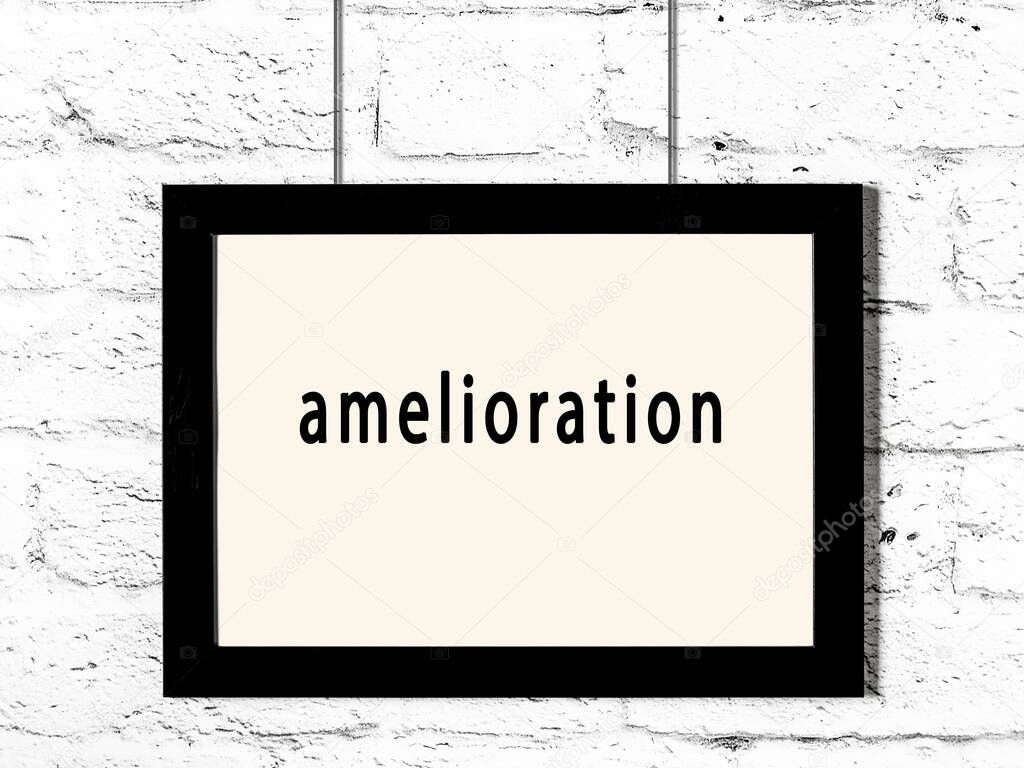 Black wooden frame with inscription amelioration hanging on white brick wall 
