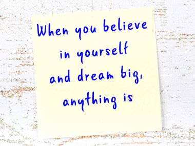 Sarı yapışkan not, ahşap duvarda el yazısıyla yazılmış zekice bir alıntıyla.