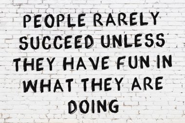 Beyaz tuğla duvara zekice alıntılar yazılı siyah bir yazı.