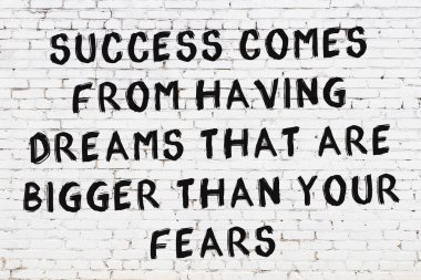 Beyaz tuğla duvar ve bilgece alıntıların yazılı olduğu siyah yazı.