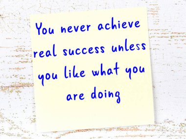 Tahta duvarda el yazısı motivasyon alıntısı olan sarı yapışkan not