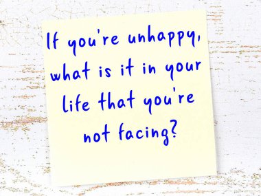 Tahta duvarda asılı sarı yapışkan nota elle yazılmış bilgece bir alıntı.