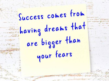 Sarı yapışkan not, ahşap duvarda el yazısıyla yazılmış zekice bir alıntıyla.