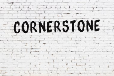 Beyaz tuğlalı duvar. Yazılı köşe taşı. Üzerinde siyah boya var.