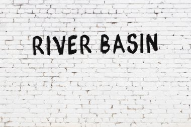 Inscription river basin written with black paint on white brick wall.
