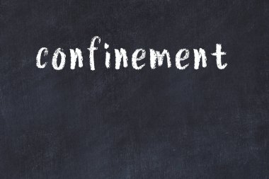 White brick wall with inscription confinement handwritten with black paint