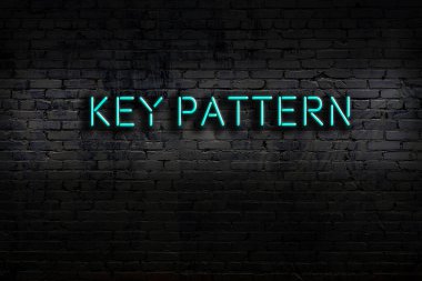 Neon sign on brick wall at night. Inscription key pattern