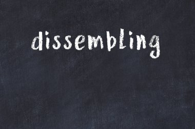 White brick wall with inscription dissembling handwritten with black paint