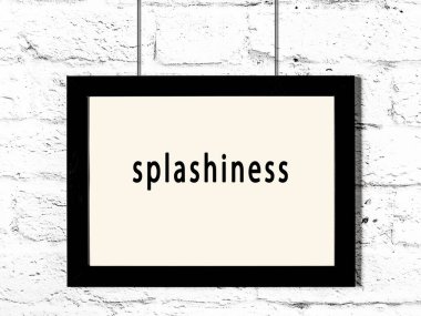 Black wooden frame with inscription splashiness hanging on white brick wall 