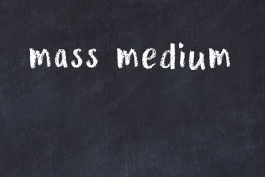 White brick wall with inscription mass medium handwritten with black paint