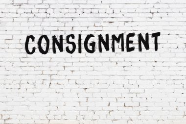 White brick wall with inscription consignment handwritten with black paint