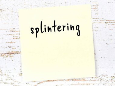 Concept of reminder about splintering. Yellow sticky sheet of paper on wooden wall with inscription
