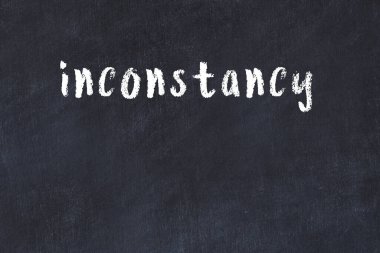 White brick wall with inscription inconstancy handwritten with black paint