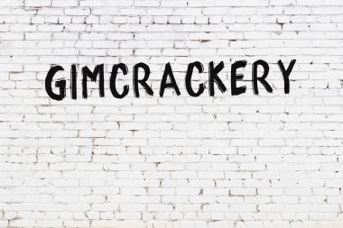 White brick wall with inscription gimcrackery handwritten with black paint