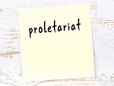 Yellow sticky note on wooden wall with handwritten inscription proletariat