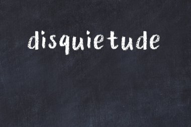 Inscription disquietude written with black paint on white brick wall.