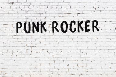 White brick wall with inscription punk rocker handwritten with black paint