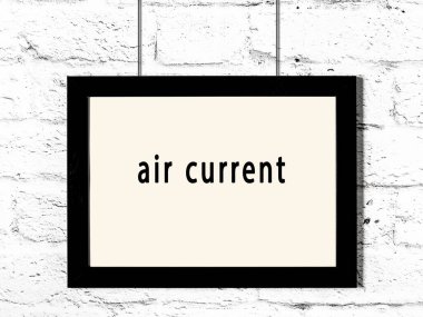 Black wooden frame with inscription air current hanging on white brick wall 
