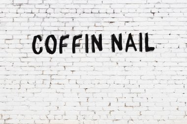 White brick wall with inscription coffin nail handwritten with black paint