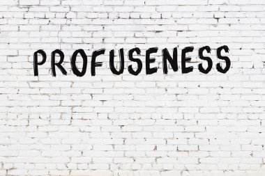 Beyaz tuğlalı duvar. Üzerinde yazı var. El yazısıyla siyah boya.