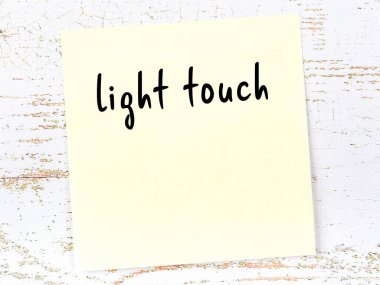 Hafif dokunuşları hatırlatma kavramı. Tahta duvarda üzerinde yazı olan sarı yapışkan kağıt.