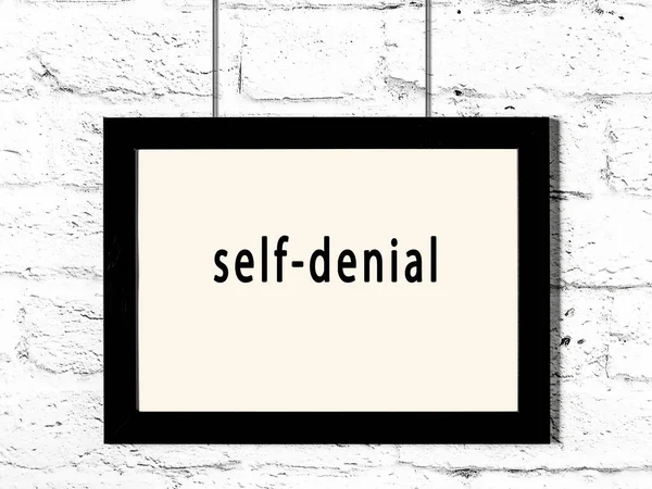 Black Wooden Frame Inscription Self Denial Hanging White Brick Wall — стоковое фото