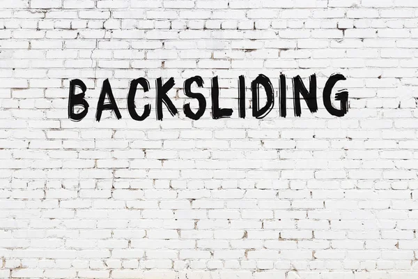 Inscription Backsliding Written Black Paint White Brick Wall — 图库照片