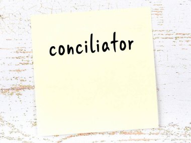 Tahta duvarda el yazısıyla yazılmış sarı yapışkan bir not var.