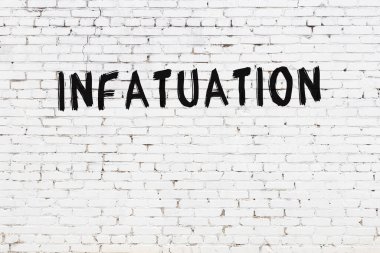 Yazı, beyaz tuğla duvara siyah boya ile yazılmış..