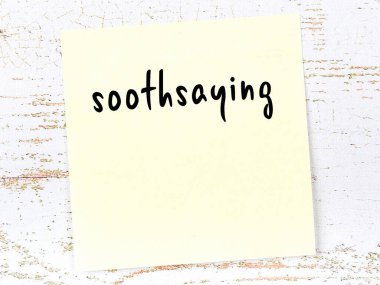 Tahta duvardaki sarı yapışkan notta el yazısıyla yazılmış kahin yazısı var.