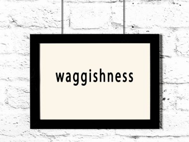 Black wooden frame with inscription waggishness hanging on white brick wall 
