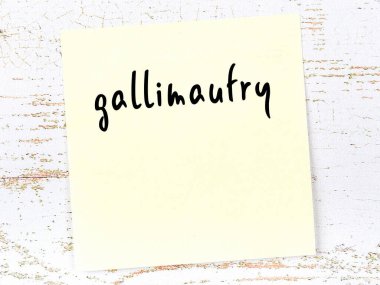 Concept of reminder about gallimaufry. Yellow sticky sheet of paper on wooden wall with inscription