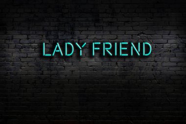 Neon sign on brick wall at night. Inscription lady friend