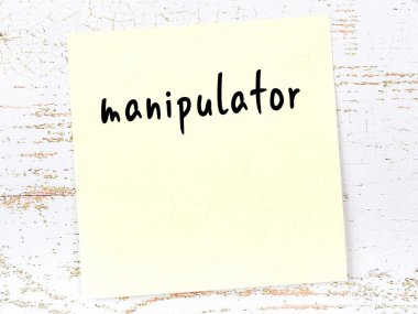 Concept of reminder about manipulator. Yellow sticky sheet of paper on wooden wall with inscription
