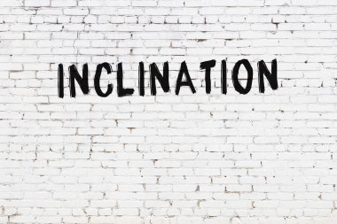 White brick wall with inscription inclination handwritten with black paint