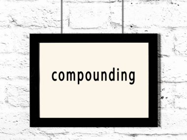 Black wooden frame with inscription compounding hanging on white brick wall 