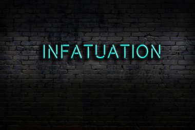Neon sign on brick wall at night. Inscription infatuation