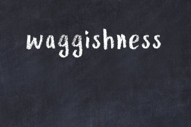 White brick wall with inscription waggishness handwritten with black paint