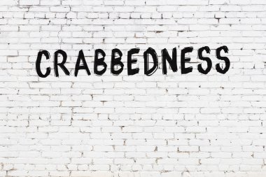 Üzerinde siyah boya ile yazılmış yengeç yazısı olan beyaz tuğla bir duvar.