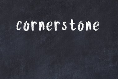 Beyaz tuğlalı duvar. Yazılı köşe taşı. Üzerinde siyah boya var.