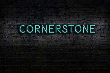 Neon sign with inscription cornerstone against brick wall. Night view