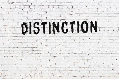 Inscription distinction written with black paint on white brick wall.