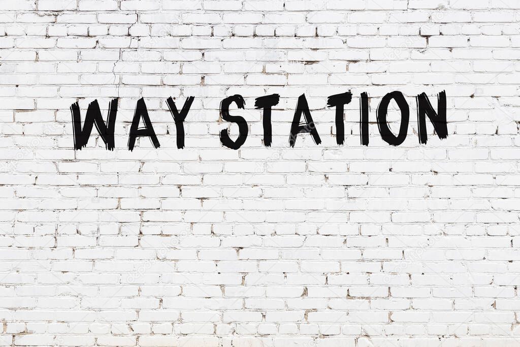Inscription way station written with black paint on white brick wall.
