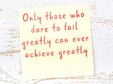 Tahta duvarda asılı sarı yapışkan nota elle yazılmış bilgece bir alıntı.