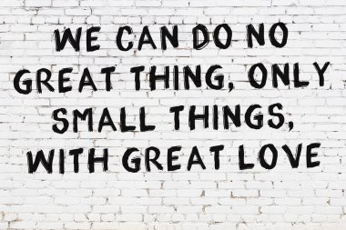 Beyaz tuğla duvara zekice alıntılar yazılı siyah bir yazı.