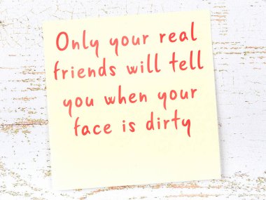 Sarı yapışkan not, ahşap duvarda el yazısıyla yazılmış zekice bir alıntıyla.