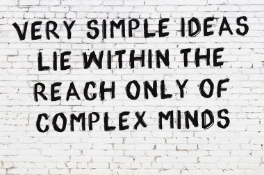 Beyaz tuğla duvara zekice alıntılar yazılı siyah bir yazı.